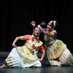 Two mohiniyattam dancers as Radha and Krishna in traditional white costumes