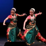 Two bharathanatyam dancers in green and red in agressive poses