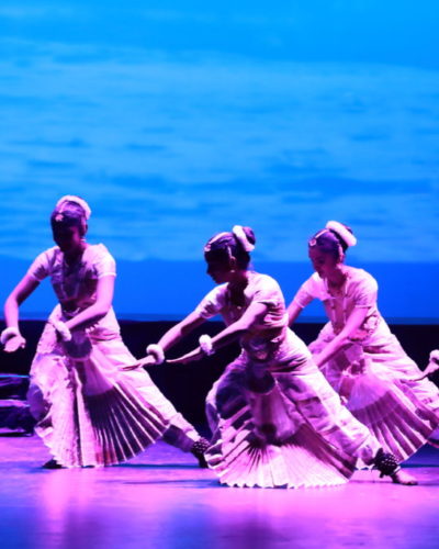 Five dancers in purple light with a blue projection behind them